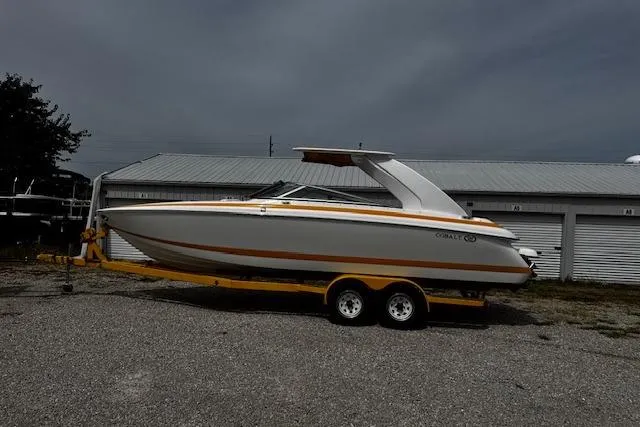 Slide: The Image of 2002 Cobalt 262 boat on trailer, parked outdoors near storage units. - 4