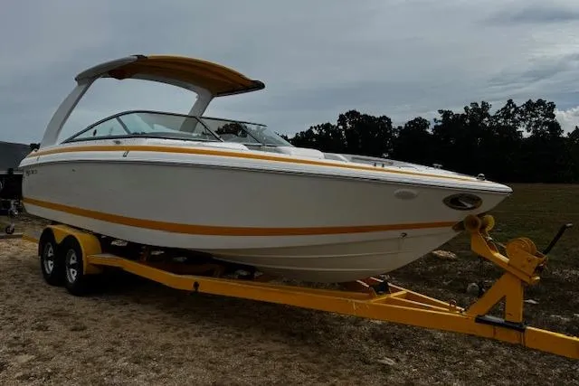Slide: The Image of 2002 Cobalt 262 boat on yellow trailer, parked outdoors on a cloudy day. - 6