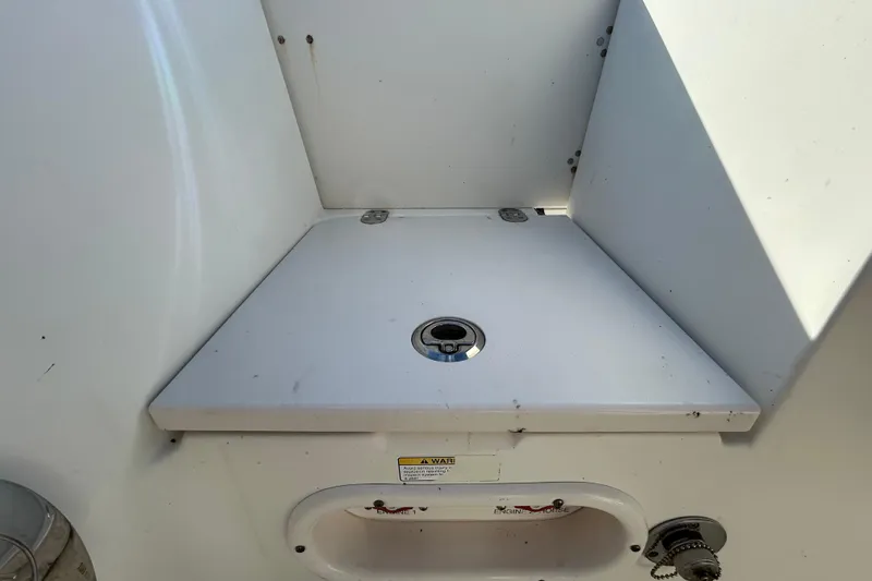 Slide: The Image of 2016 NauticStar 25 XS boat compartment with white interior and metal fittings. - 49