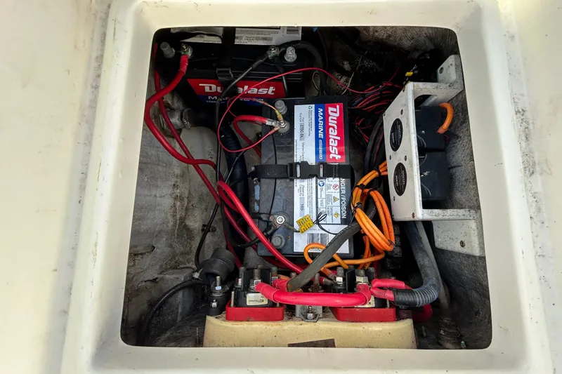 Slide: The Image of 2016 NauticStar 25 XS boat battery compartment with Duralast marine battery and wiring. - 51