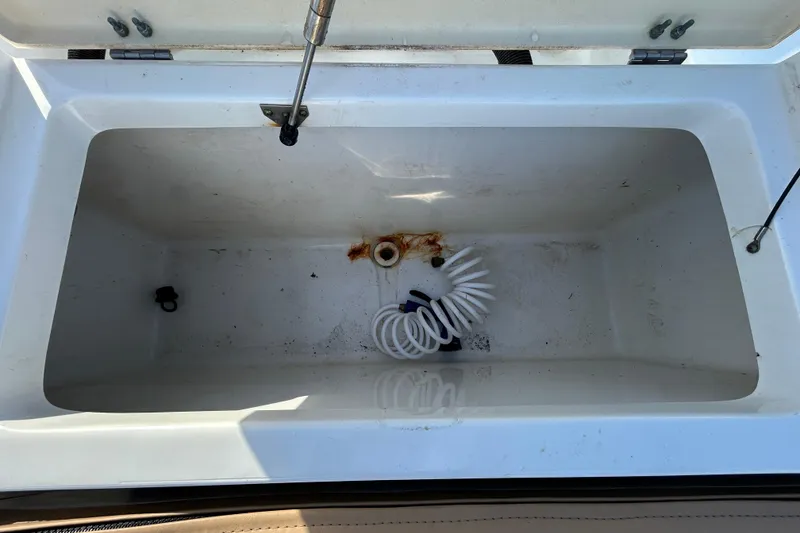 Slide: The Image of Open storage compartment on 2016 NauticStar 25 XS boat, featuring a coiled hose. - 56