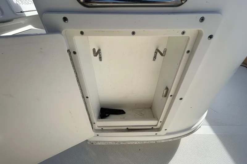 Slide: The Image of Open storage compartment on 2016 NauticStar 25 XS boat, showing interior hooks. - 65
