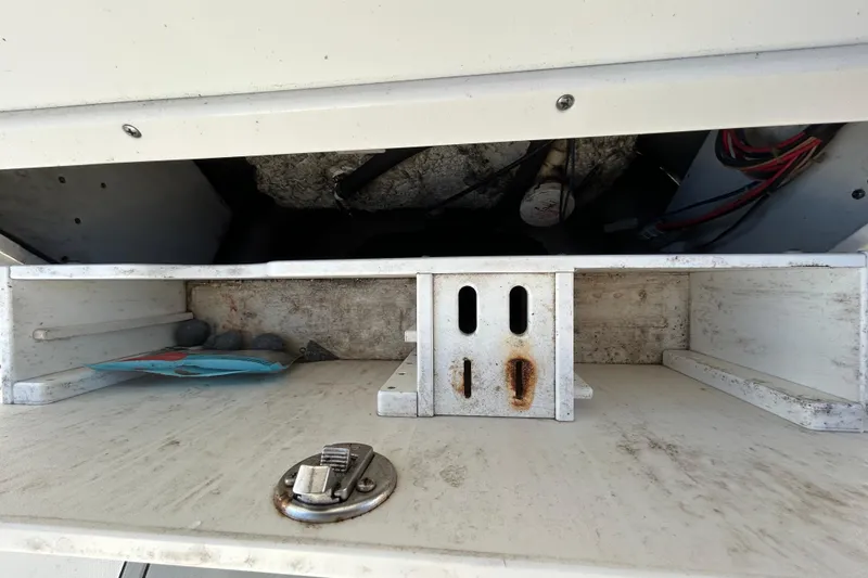 Slide: The Image of 2016 NauticStar 25 XS boat storage compartment with rust and wiring visible. - 69