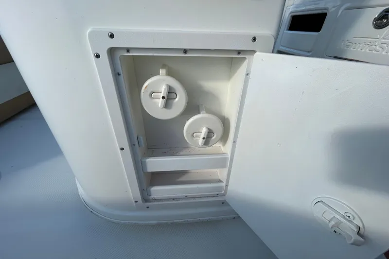 Slide: The Image of Open compartment on 2016 NauticStar 25 XS boat showing interior valves and controls. - 71