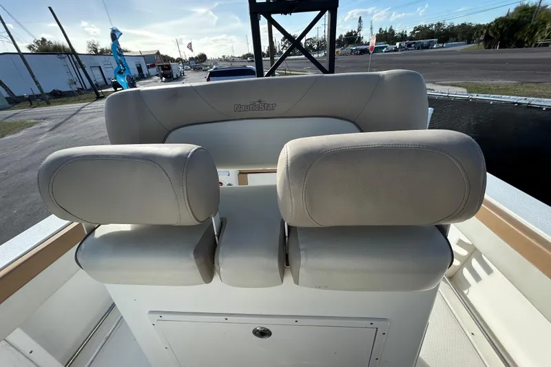 Slide: The Image of 2016 NauticStar 25 XS boat seating with beige upholstery, outdoor setting. - 73