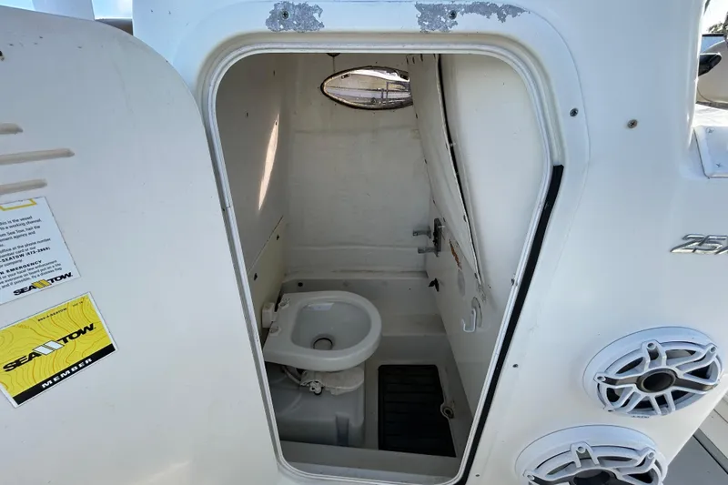 Slide: The Image of 2016 NauticStar 25 XS boat interior with compact marine toilet and storage space. - 79