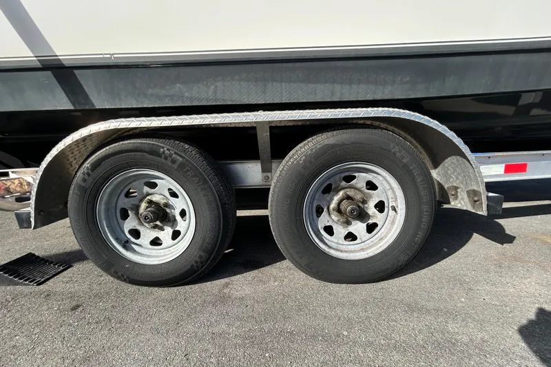 Slide: The Image of Trailer wheels of a 2016 NauticStar 25 XS boat on pavement. - 96