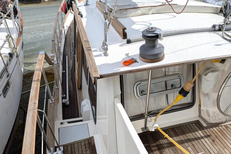 Slide: The Image of 1985 Siltala Nauticat 44 sailboat deck with winch and wooden railings. - 19