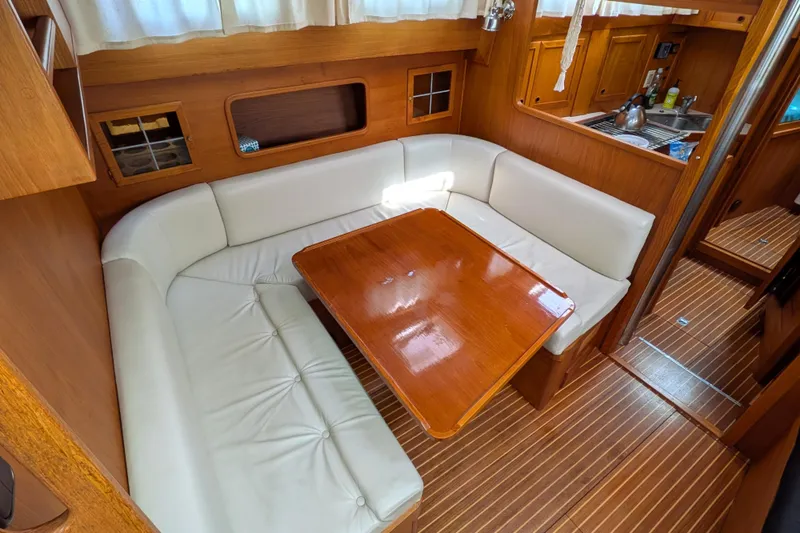 Slide: The Image of Cozy dining area in 1985 Siltala Nauticat 44 yacht with wooden table and white seating. - 38