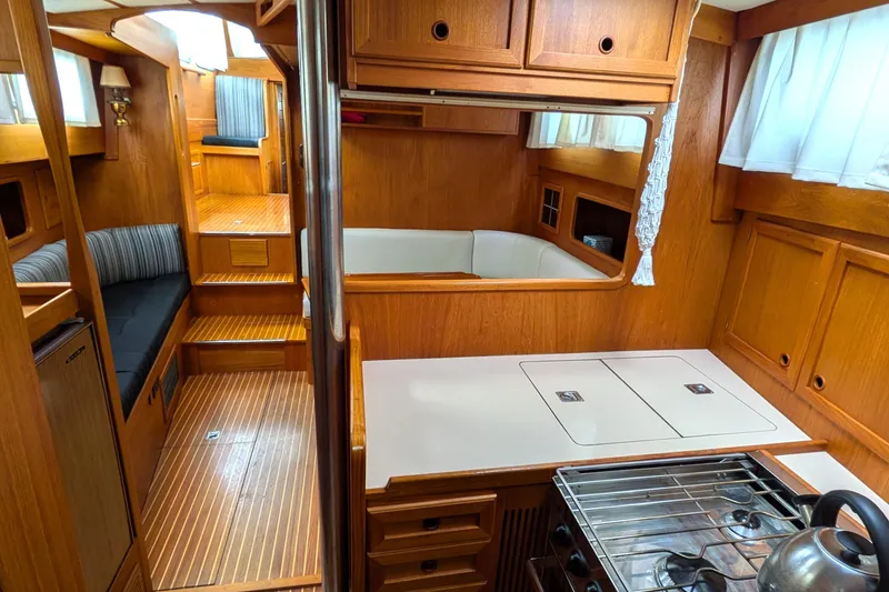 Slide: The Image of Interior of 1985 Siltala Nauticat 44 yacht, featuring wood paneling and compact kitchen area. - 47