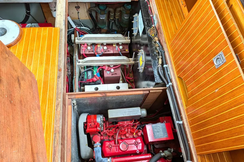 Slide: The Image of Engine compartment of a 1985 Siltala Nauticat 44 sailboat, showcasing red machinery and wooden paneling. - 71