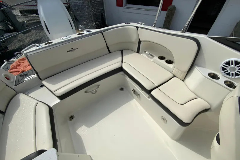 Slide: The Image of 2023 Stingray 231 DC boat interior with cushioned seating and cup holders. - 14
