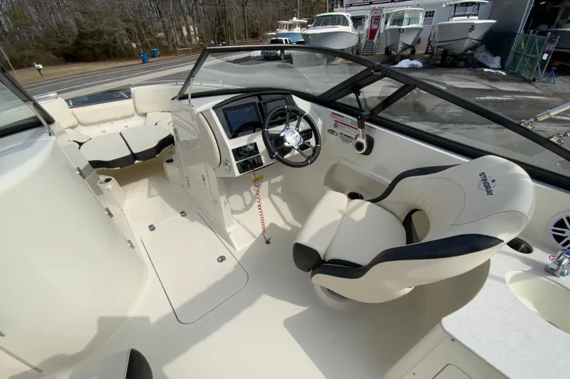 Slide: The Image of 2023 Stingray 231 DC boat interior with steering wheel and seating area. - 16