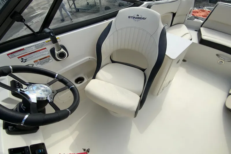 Slide: The Image of 2023 Stingray 231 DC boat interior with steering wheel and captain's chair. - 22