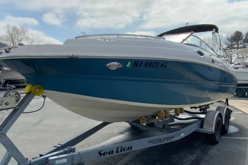 Slide: The Image of 2023 Stingray 231 DC boat on trailer, blue and white design, parked outdoors. - 5
