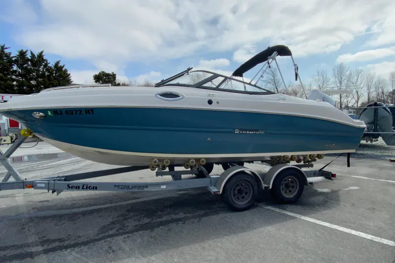 Slide: The Image of 2023 Stingray 231 DC boat on trailer, parked outdoors under cloudy sky. - 6