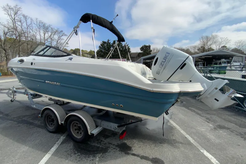 Slide: The Image of 2023 Stingray 231 DC boat on trailer with Suzuki outboard motor in parking lot. - 7