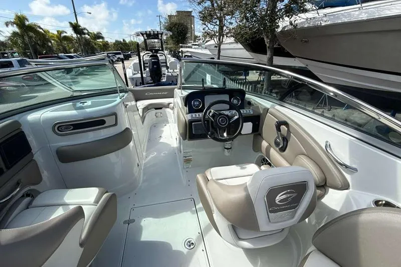 Slide: The Image of 2021 Crownline 255 XSS boat interior with steering wheel and seating, docked outdoors. - 12