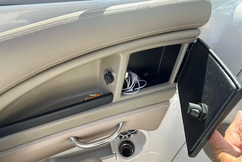 Slide: The Image of 2021 Crownline 255 XSS boat storage compartment with open door and visible accessories. - 22
