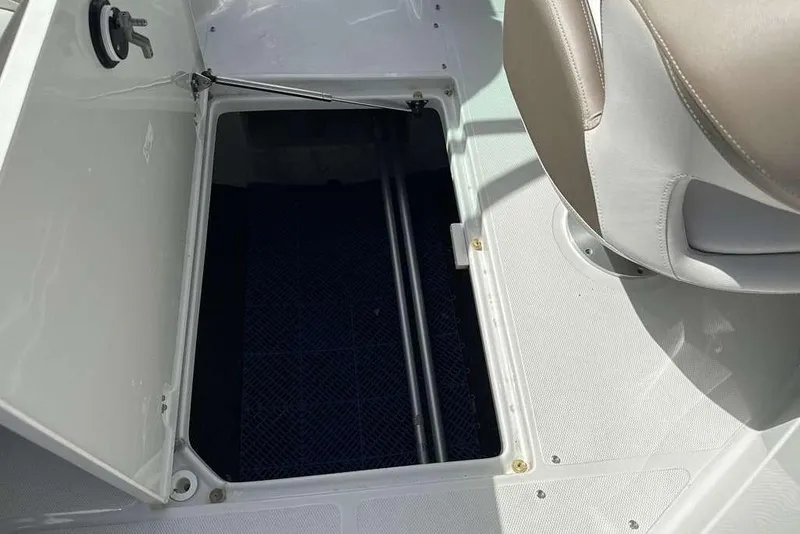 Slide: The Image of Open storage compartment on 2021 Crownline 255 XSS boat, next to a beige seat. - 27