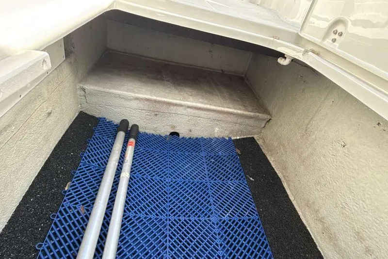 Slide: The Image of Storage compartment of 2021 Crownline 255 XSS boat with blue mat and poles. - 28