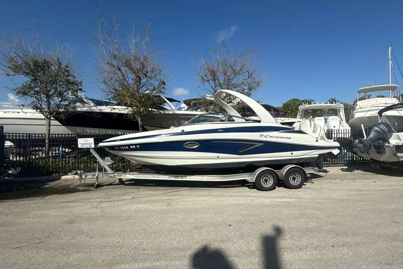 Slide: The Image of 2021 Crownline 255 XSS boat on trailer, parked outdoors under clear blue sky. - 42