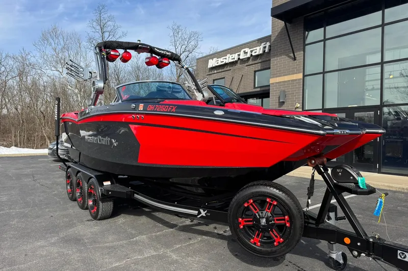 The Image of 2020 MasterCraft XStar boat in red and black on a trailer outside dealership. - 1