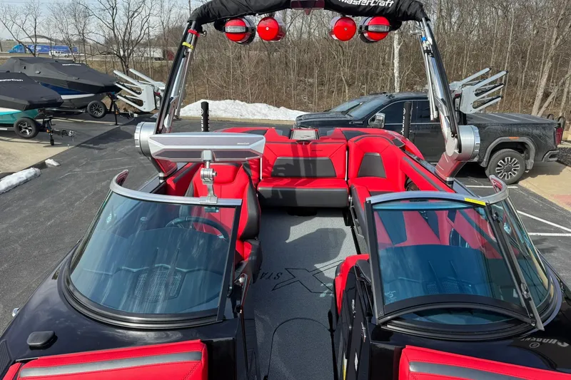 Slide: The Image of 2020 MasterCraft XStar boat with red interior and sleek design, parked outdoors. - 16