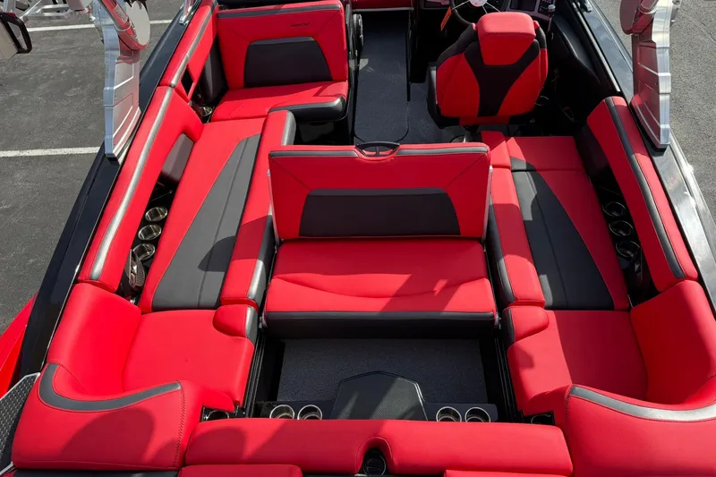 Slide: The Image of 2020 MasterCraft XStar boat interior with red and black seating, cup holders, and steering wheel. - 25