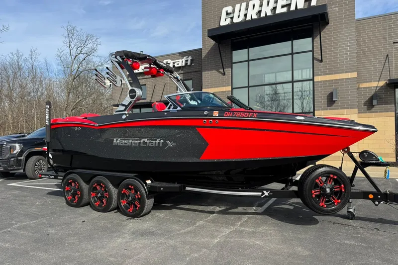 Slide: The Image of 2020 MasterCraft XStar boat in red and black on a trailer outside a building. - 4