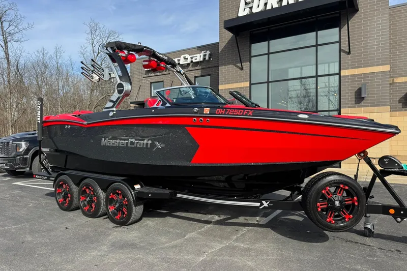 Slide: The Image of 2020 MasterCraft XStar boat in red and black on a trailer outside a building. - 5