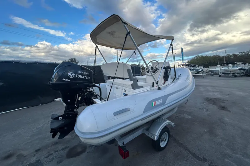 Slide: The Image of 2021 AB Inflatables Mares 10 VSX boat with Tohatsu engine on trailer, under cloudy sky. - 2