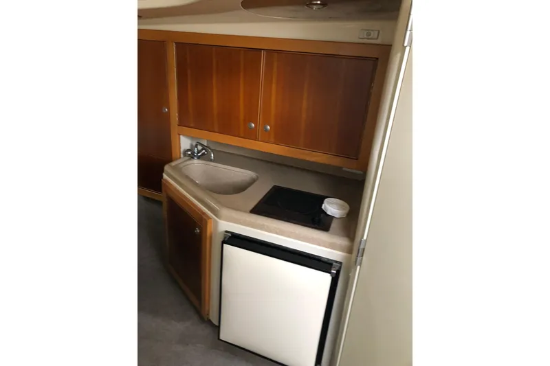 Slide: The Image of Compact kitchenette in 2000 Riviera 3000 Offshore boat with sink, stove, and fridge. - 13