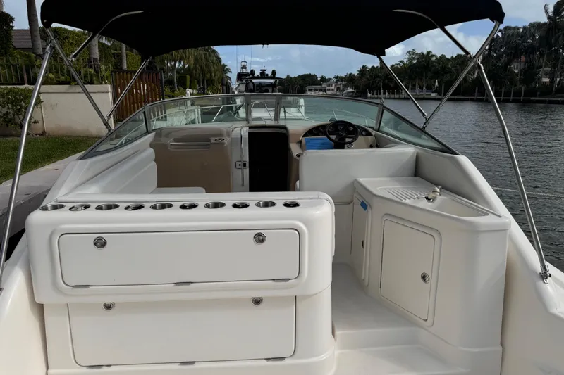 Slide: The Image of 2000 Riviera 3000 Offshore boat interior with seating and steering wheel, docked by a canal. - 15