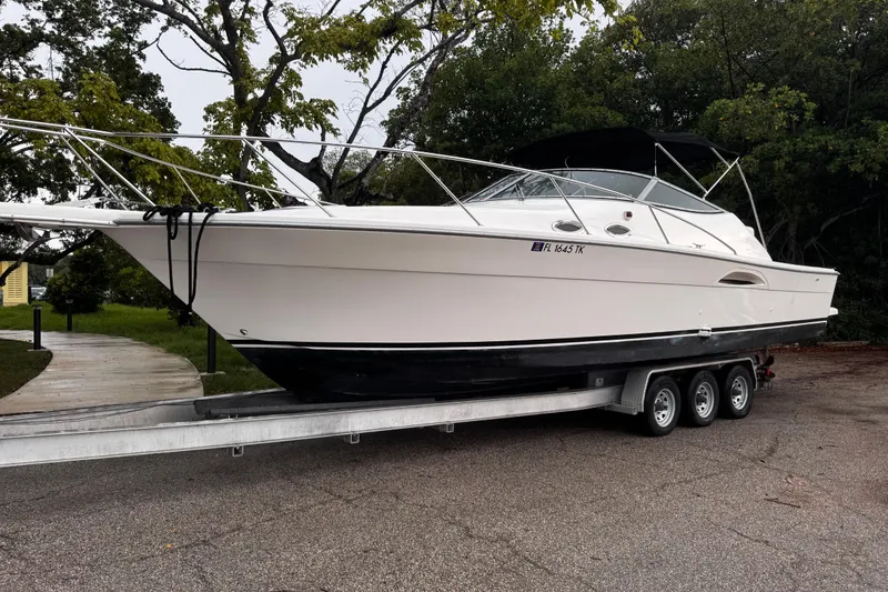 Slide: The Image of 2000 Riviera 3000 Offshore boat on a trailer, parked near trees. - 26