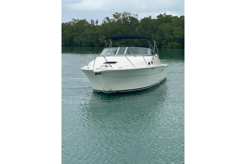 Slide: The Image of 2000 Riviera 3000 Offshore boat on calm water with lush green background. - 3