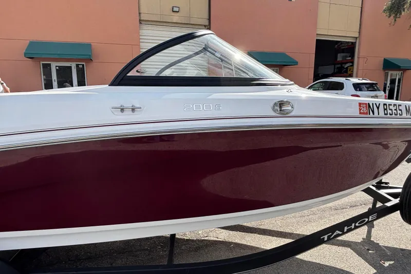 Slide: The Image of 2023 Tahoe 200 S boat with maroon and white exterior, parked on a trailer. - 4