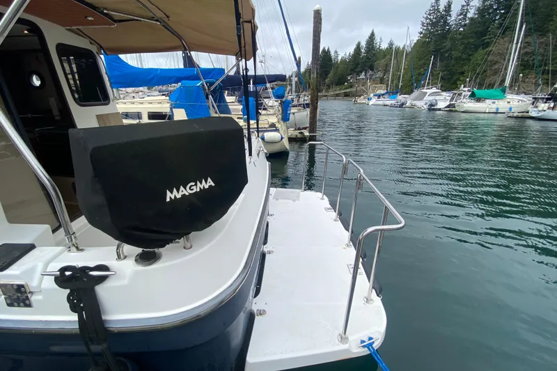 Slide: The Image of 2010 Ranger Tugs R-29 docked, featuring a covered Magma grill and spacious deck. - 10