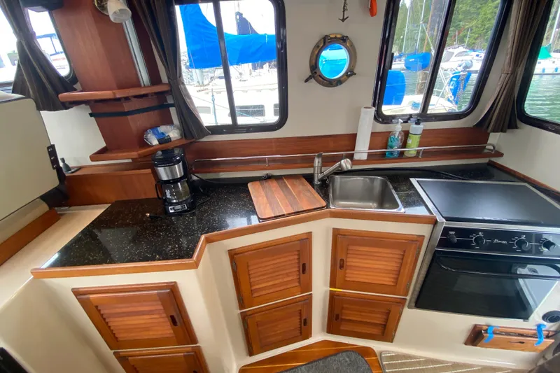 Slide: The Image of 2010 Ranger Tugs R-29 boat kitchen with sink, stove, and wooden cabinets. - 28