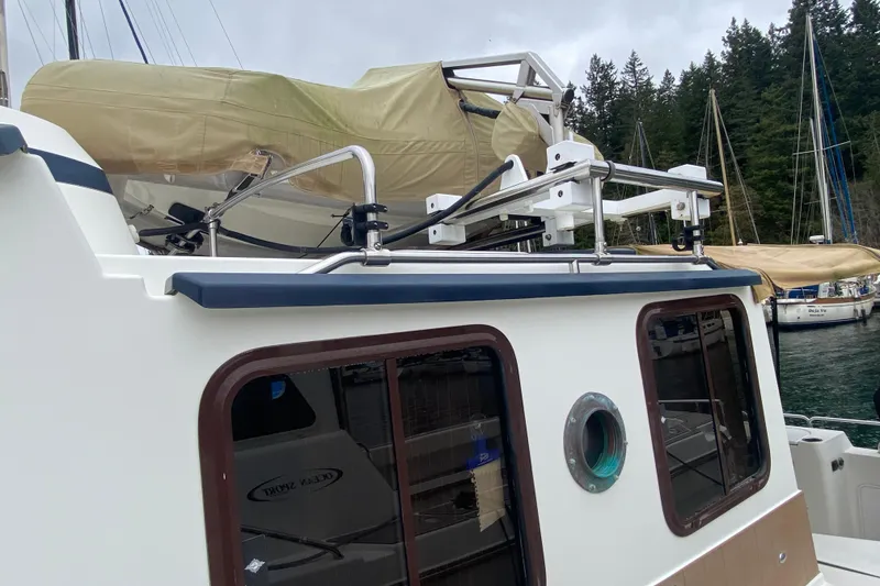 Slide: The Image of 2010 Ranger Tugs R-29 boat with covered equipment, docked near forested shoreline. - 5