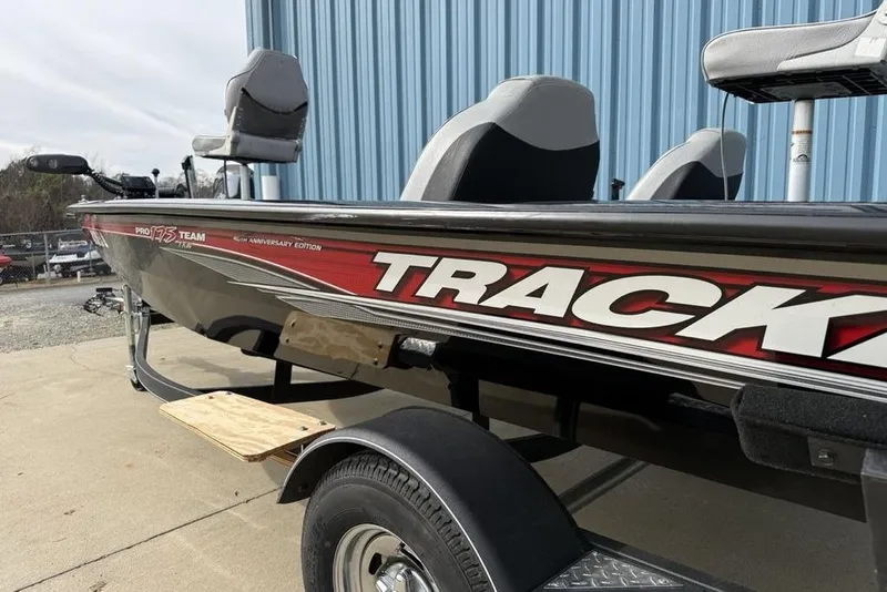 Slide: The Image of 2018 Tracker Pro Team 175 TXW boat, red and black, parked near blue building. - 7