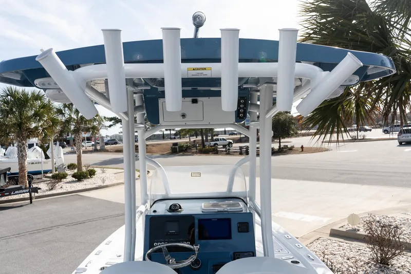 Slide: The Image of 2026 Sea Pro 230 Bay boat with T-top and rod holders, parked near palm trees. - 5