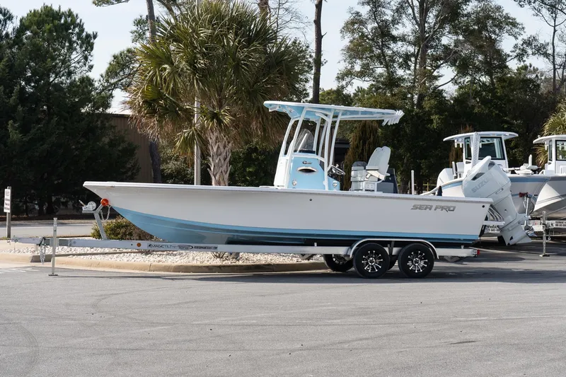 The Image of 2026 Sea Pro 250 Bay boat on trailer, parked outdoors with trees in background. - 1