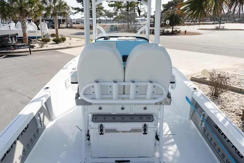 Slide: The Image of 2026 Sea Pro 250 Bay boat interior with seating and storage, docked near palm trees. - 8