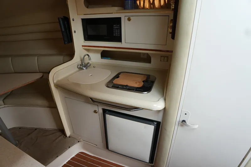 Slide: The Image of 2000 Sea Ray 270 Sundancer cabin kitchen with sink, stove, microwave, and seating area. - 20