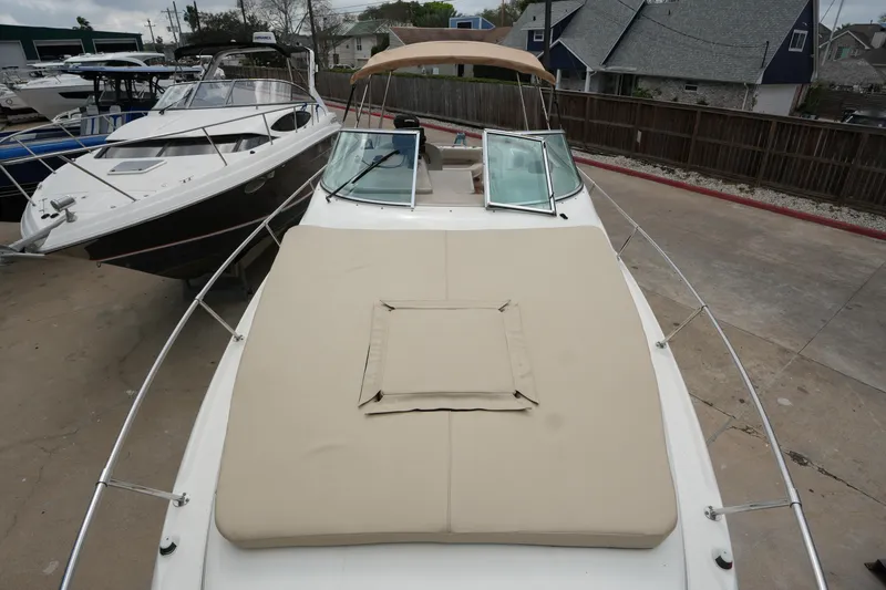 Slide: The Image of 2000 Sea Ray 270 Sundancer boat with beige sunpad, docked alongside other boats. - 9