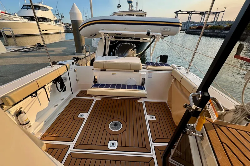 Slide: The Image of 2024 Ranger Tugs R-27 boat interior with teak flooring at a marina. - 17