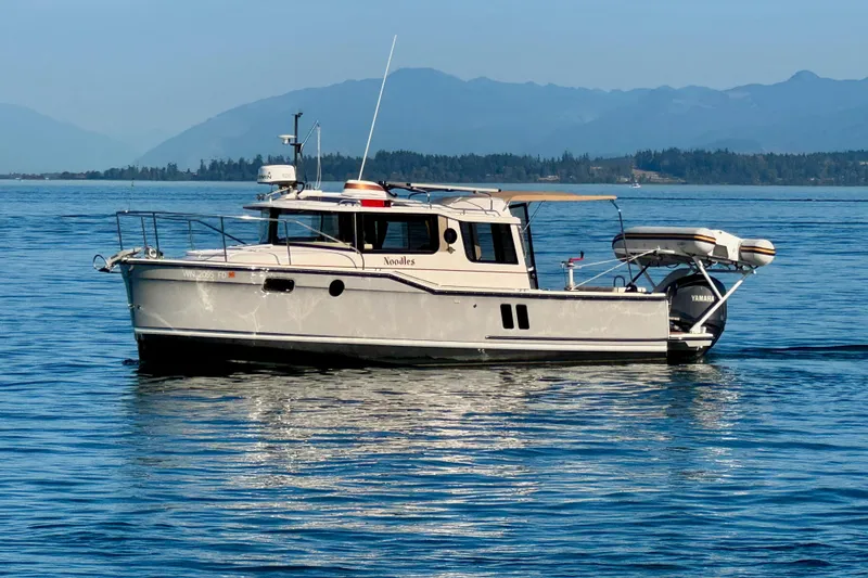 Slide: The Image of 2024 Ranger Tugs R-27 boat on calm water with scenic mountain backdrop. - 21