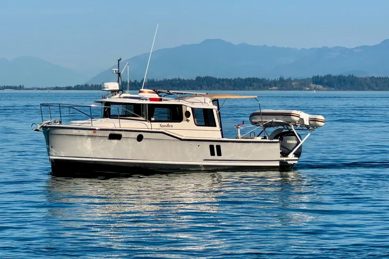 Slide: The Image of 2024 Ranger Tugs R-27 boat on calm water with scenic mountain backdrop. - 22