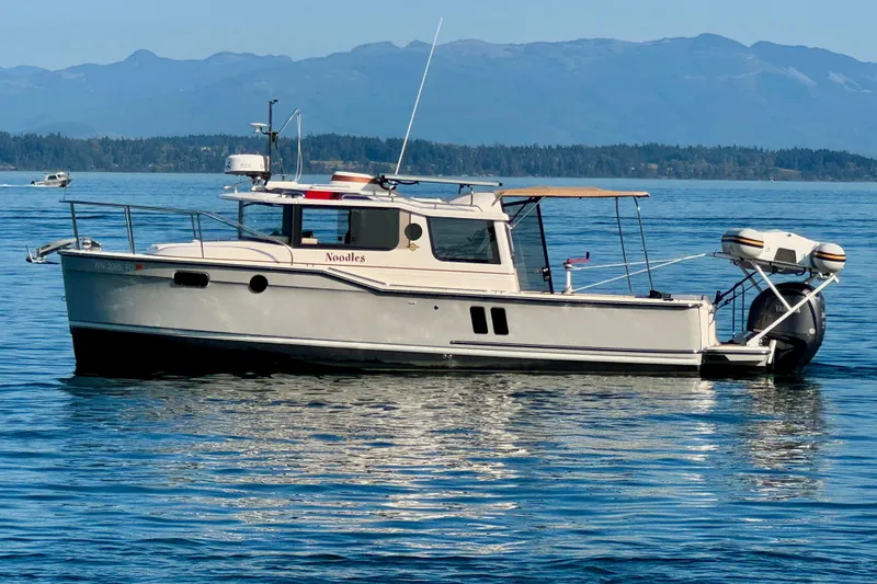 Slide: The Image of 2024 Ranger Tugs R-27 boat on calm water with scenic mountain backdrop. - 3